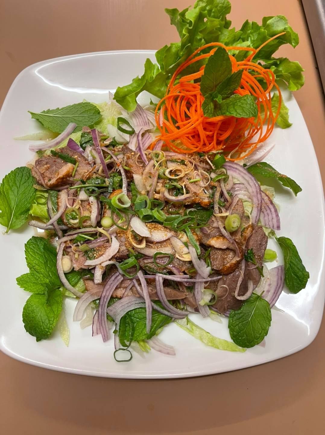 A White Plate Topped With Meat And Vegetables On A Table — Thai Taste Restaurant In Norman Gardens, QLD