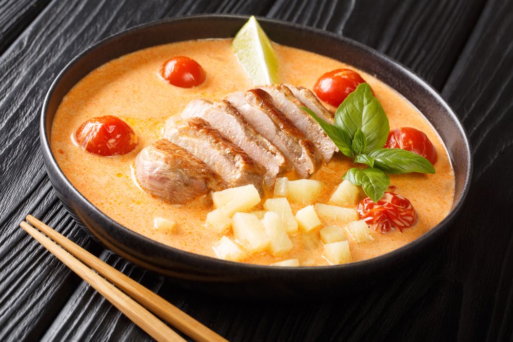 A Bowl of Soup With Meat, Pineapple, Tomatoes and Chopsticks on a Table — Thai Taste Restaurant In Norman Gardens, QLD