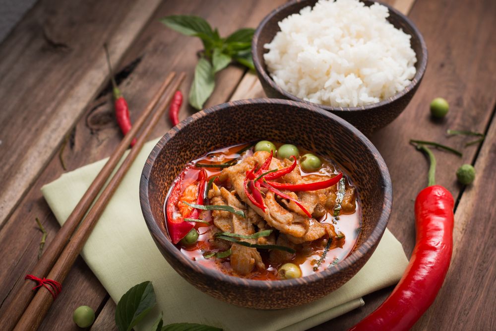 A Bowl of Chicken Curry With Rice and Chopsticks on a Wooden Table — Thai Taste Restaurant In Norman Gardens, QLD