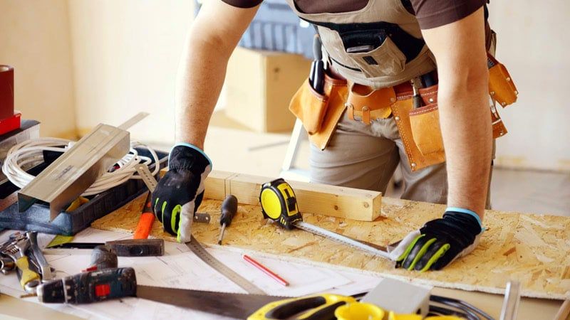 A Man Is Using A Hammer To Break A Wall — JohnCorp Property Maintenance In Emerald, QLD