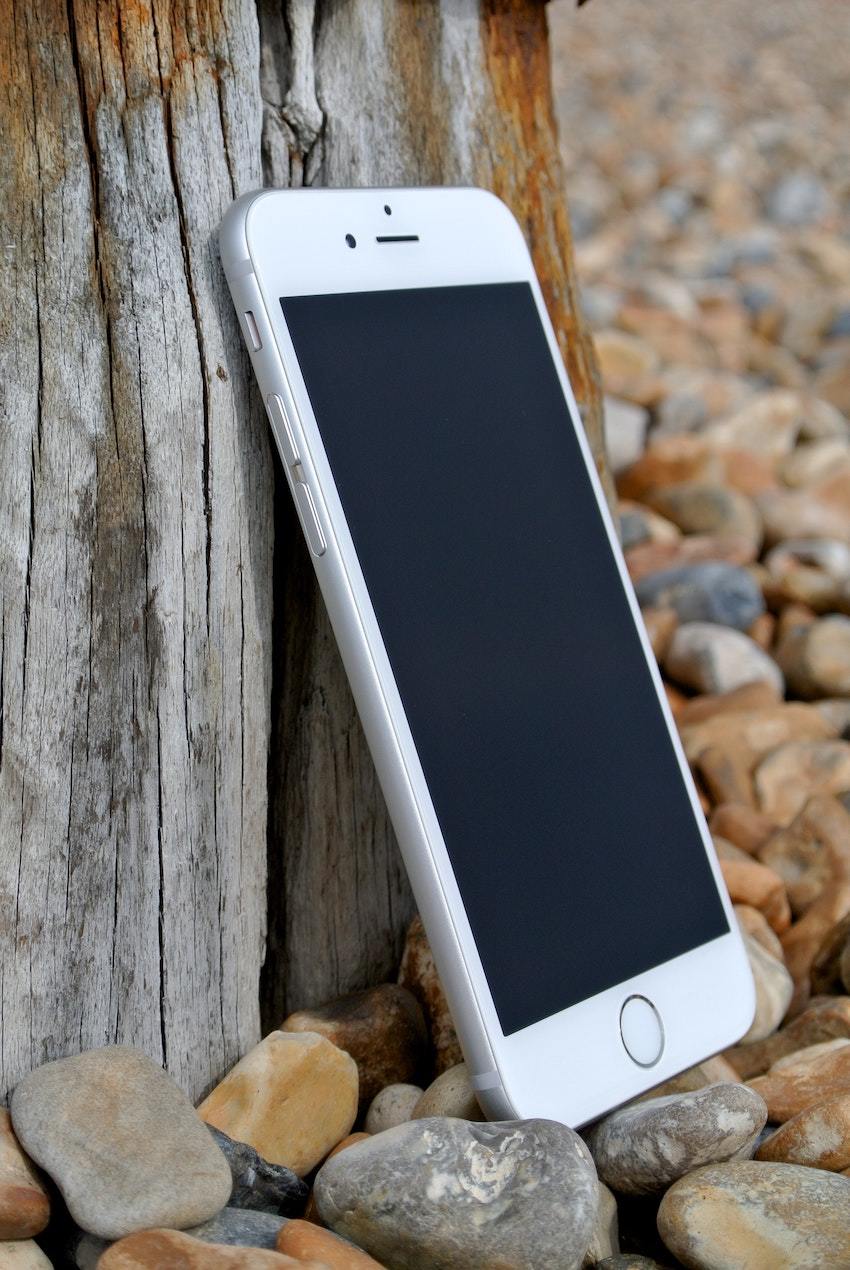 A white cell phone laying on a pile of rocks