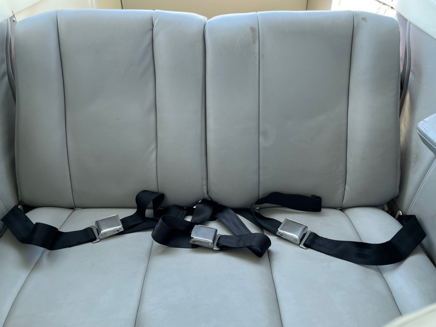 The back seat of a car with seat belts on it