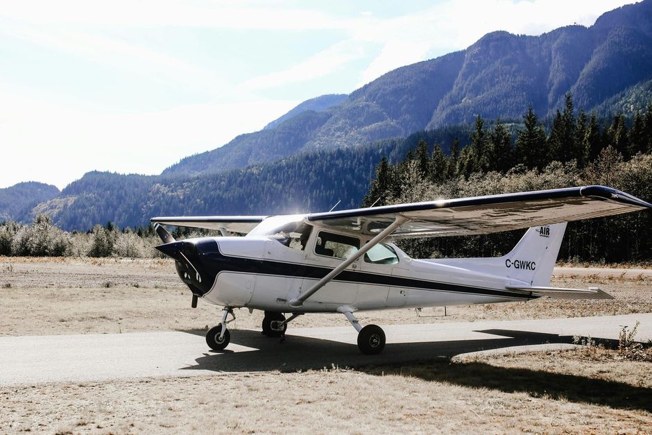 A small plane is parked on a runway with mountains in the background