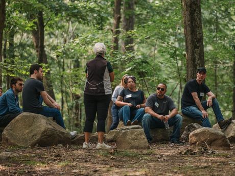 A group of people are sitting on rocks in the woods