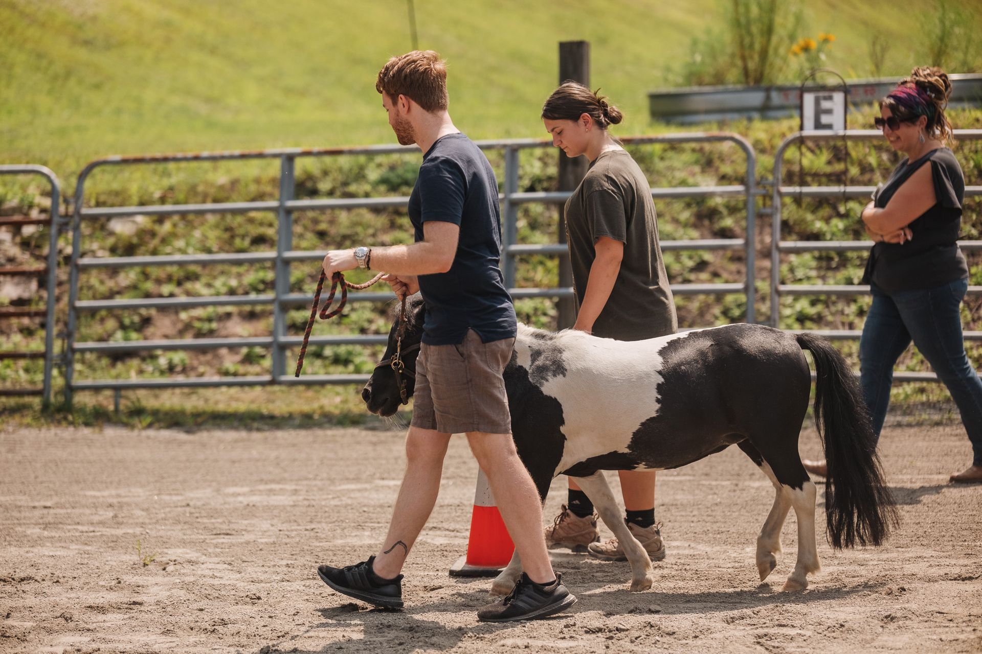 A woman is standing next to a child riding a horse