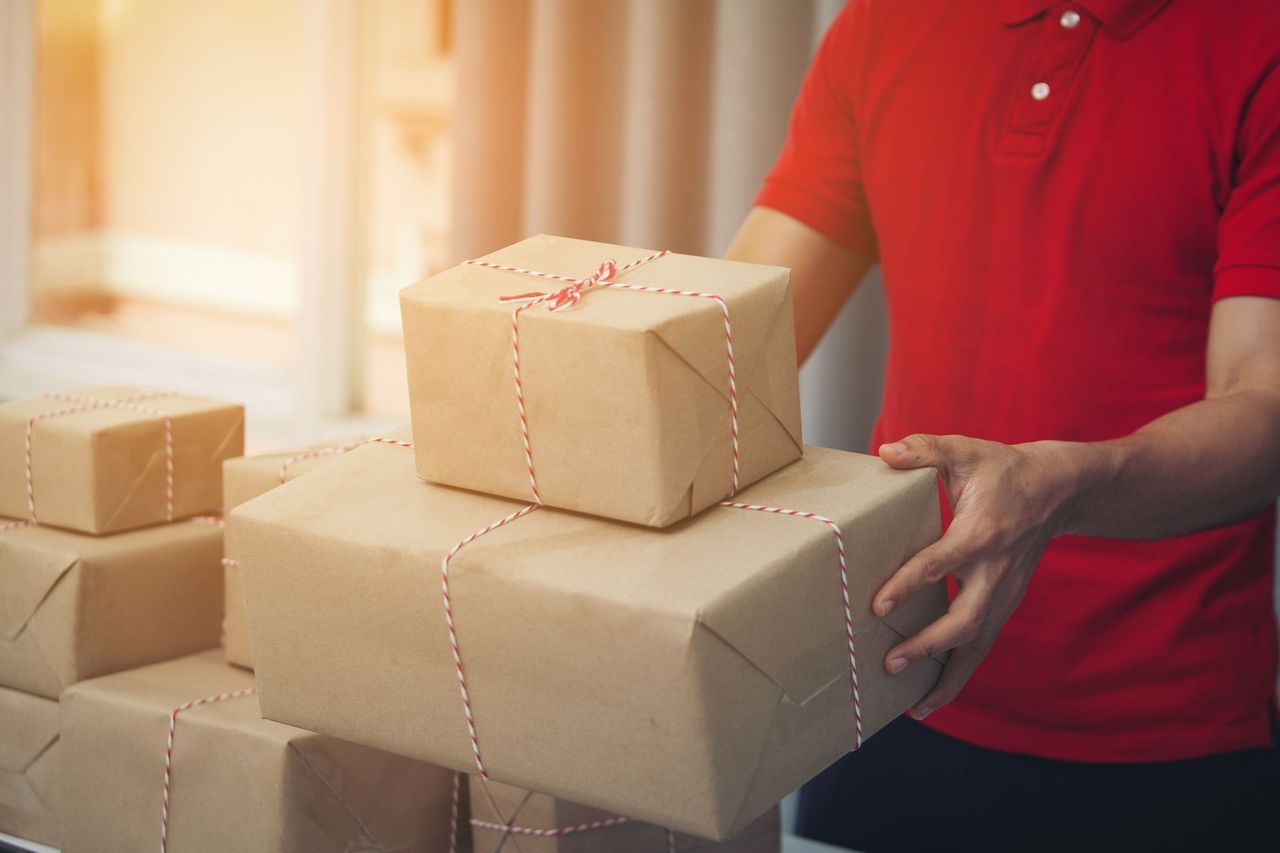 Person in red shirt stacking brown cardboard packages.