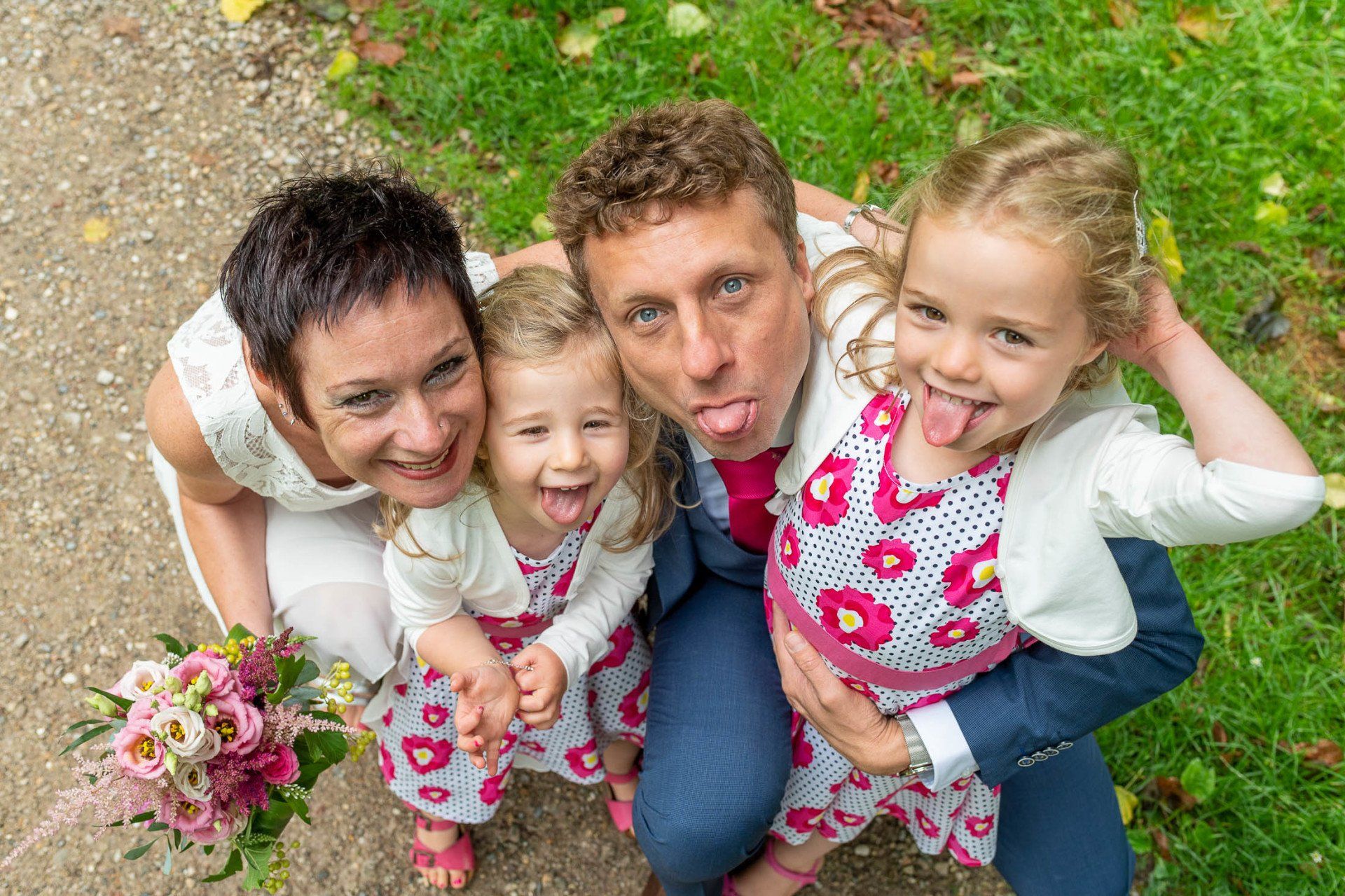 Een bruid en bruidegom poseren voor een foto met hun twee dochters.