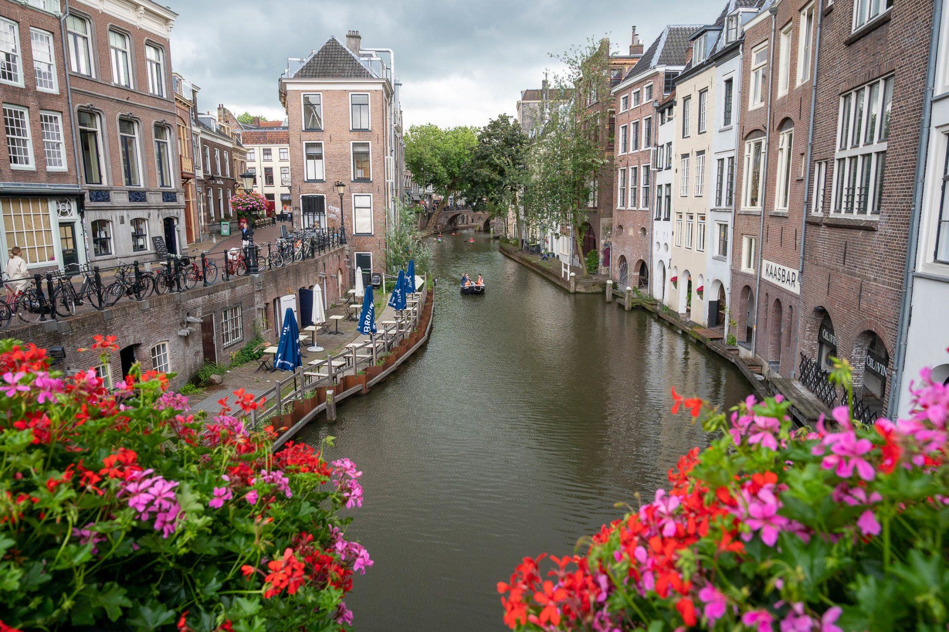 Een kanaal in een stad met bloemen op de voorgrond en een boot op de achtergrond.