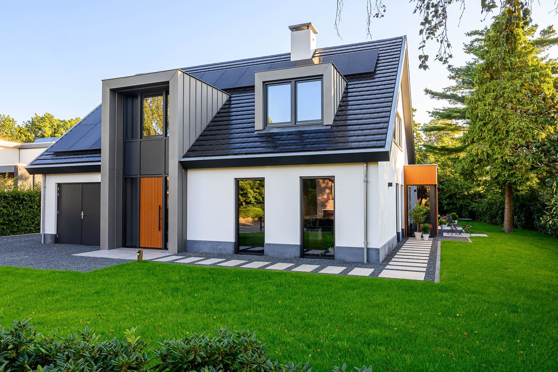 Een wit huis met een zwart dak en veel ramen