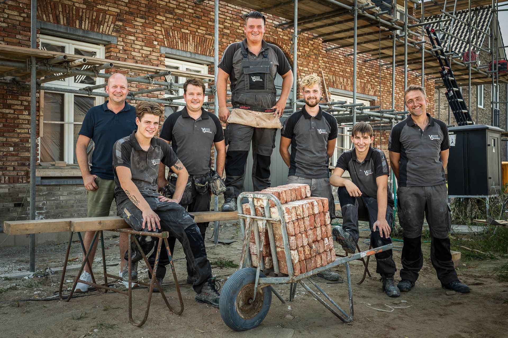 Een groep bouwvakkers poseert voor een foto voor een gebouw in aanbouw.