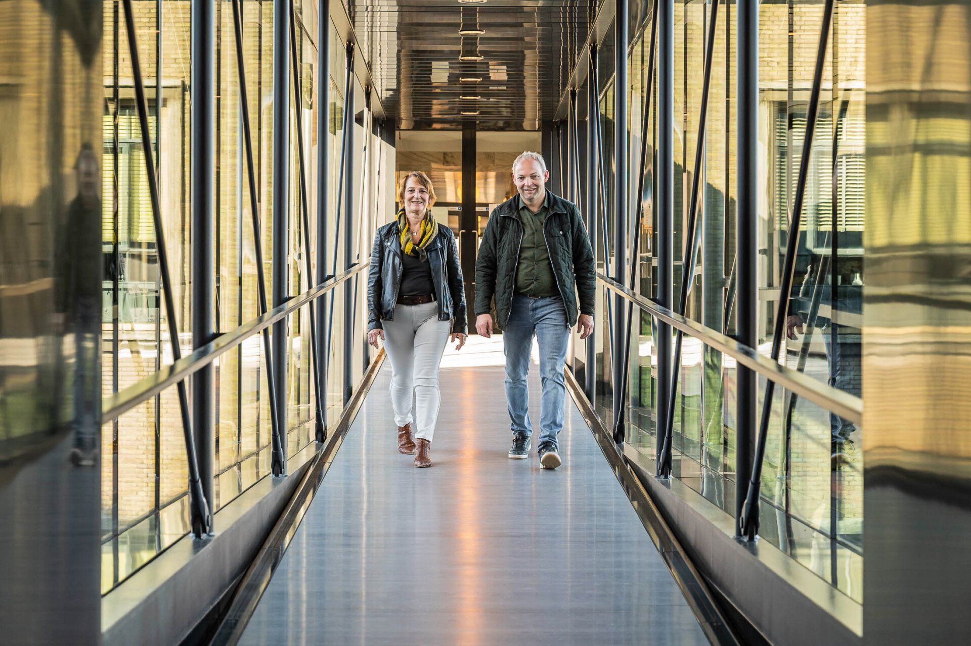 Een man en een vrouw lopen door een gang in een gebouw.