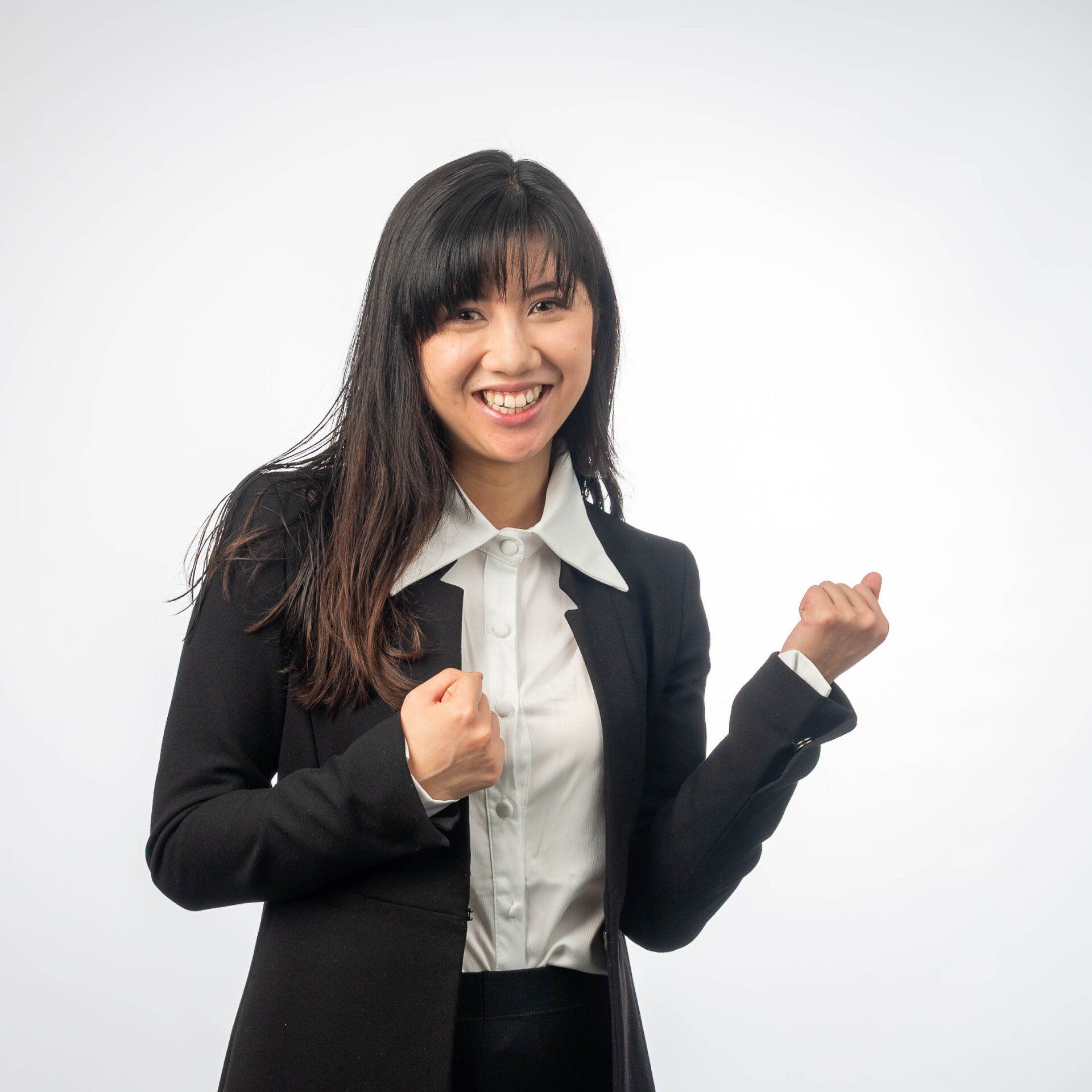 Een vrouw in een zwart jasje en een wit shirt lacht