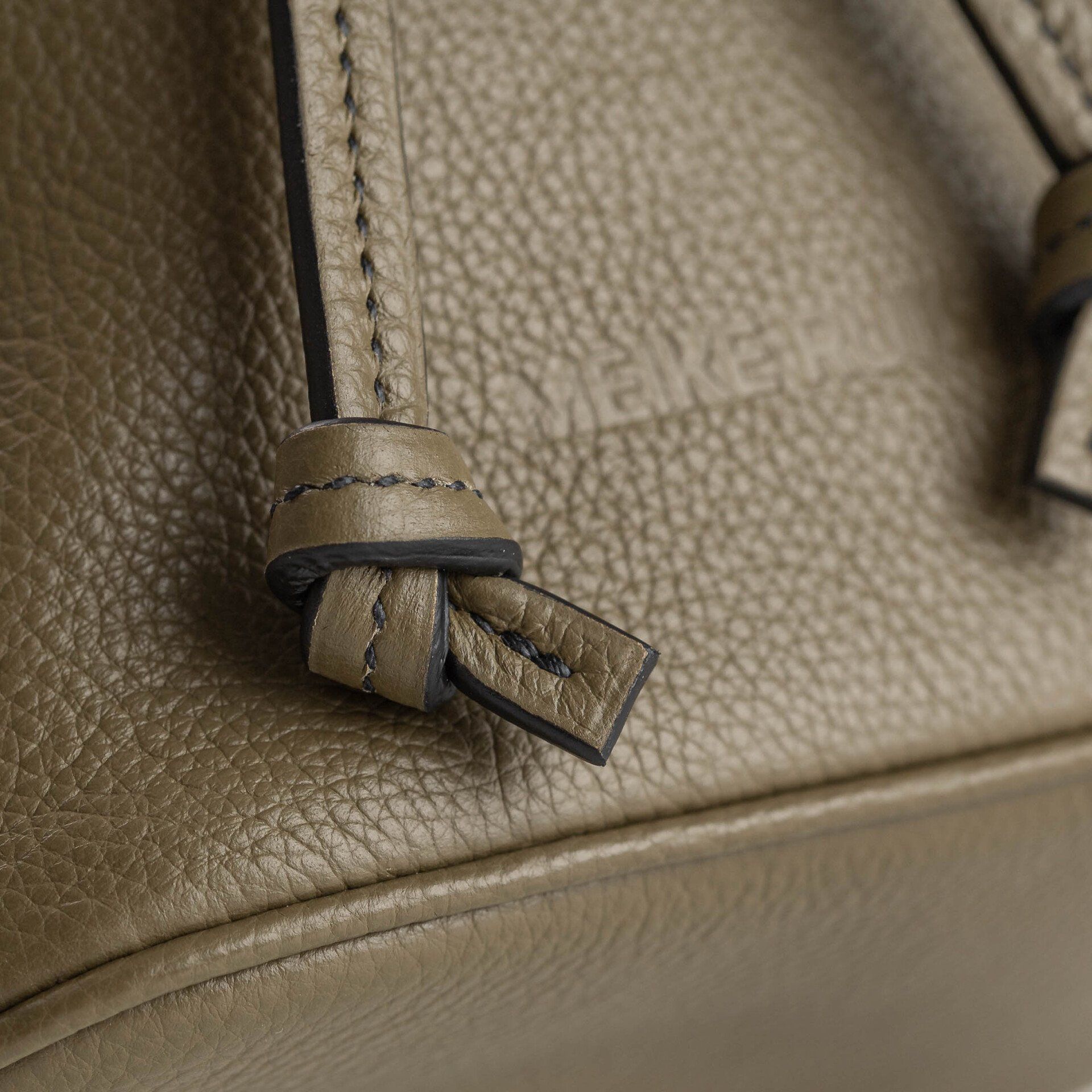 Een close-up van een bruine leren tas met een zwarte riem.