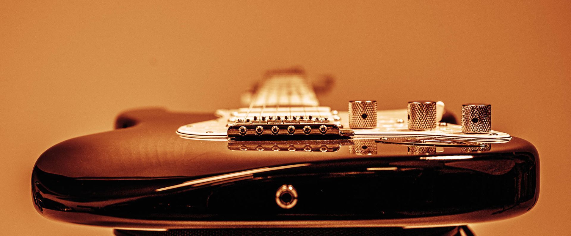 Een close-up van de achterkant van een elektrische gitaar op een standaard.