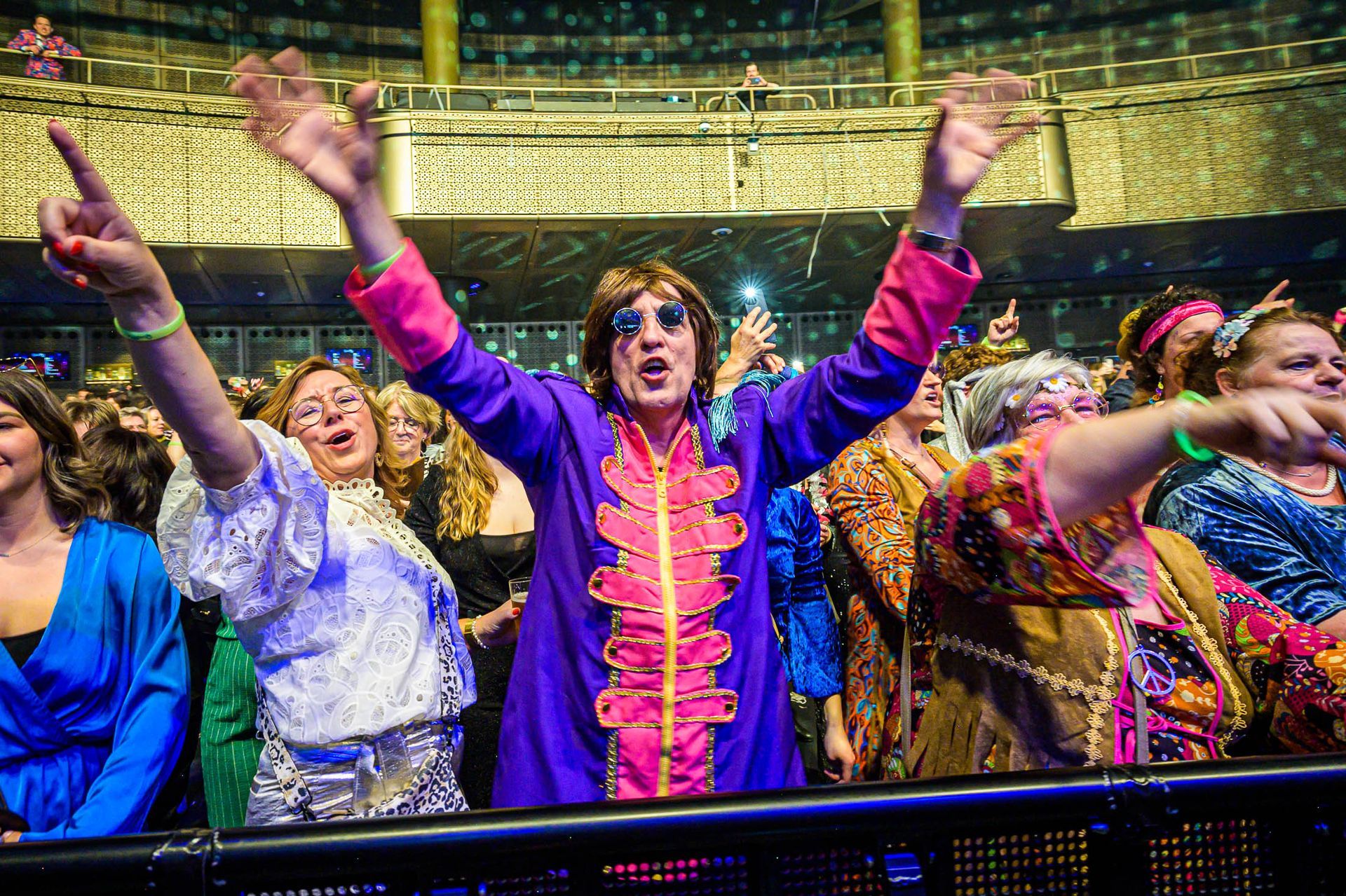 Een groep mensen staat in een stadion met hun armen in de lucht.