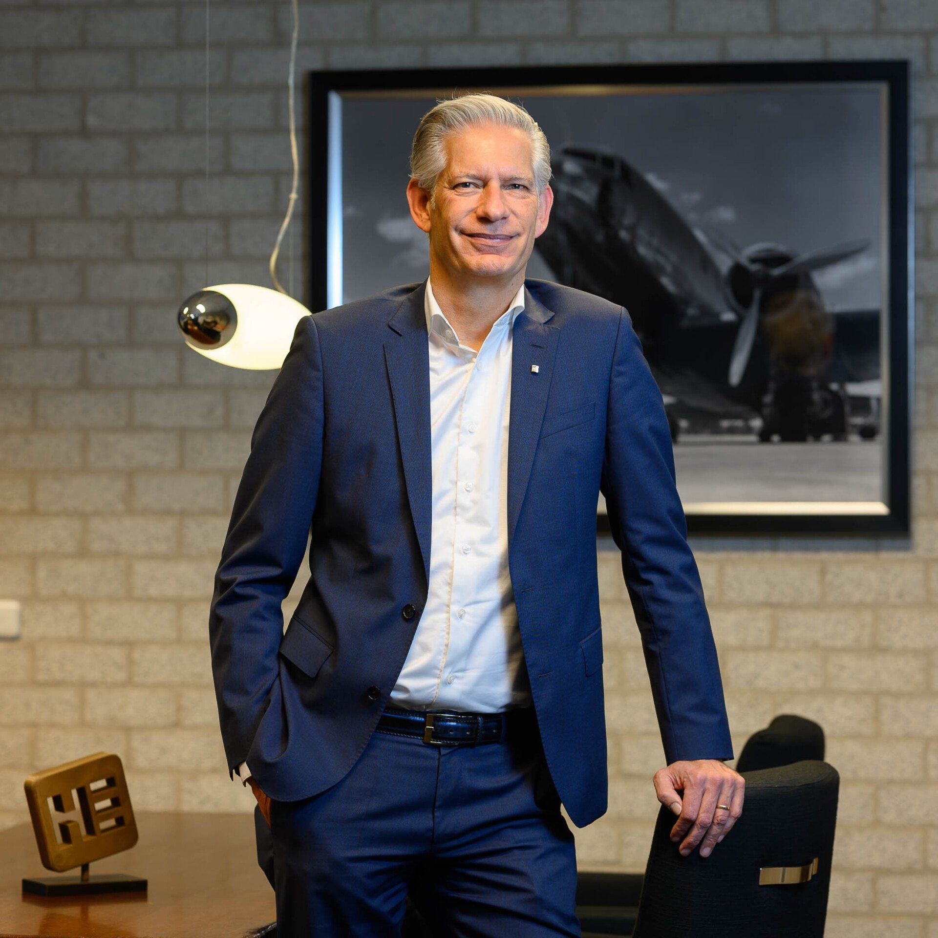 Een man in pak staat voor een afbeelding van een vliegtuig