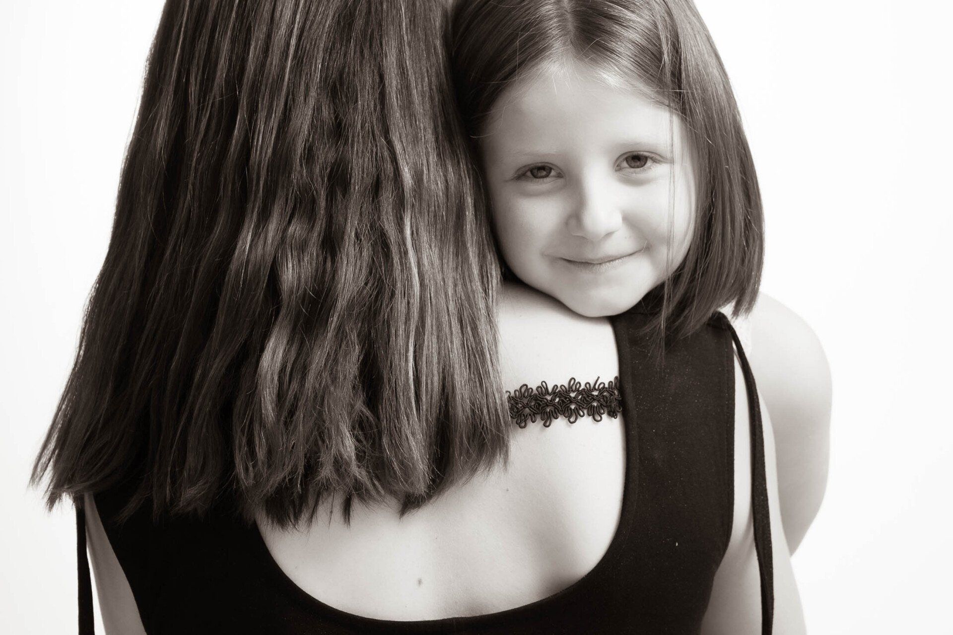 Een zwart-witfoto van een klein meisje dat haar moeder knuffelt
