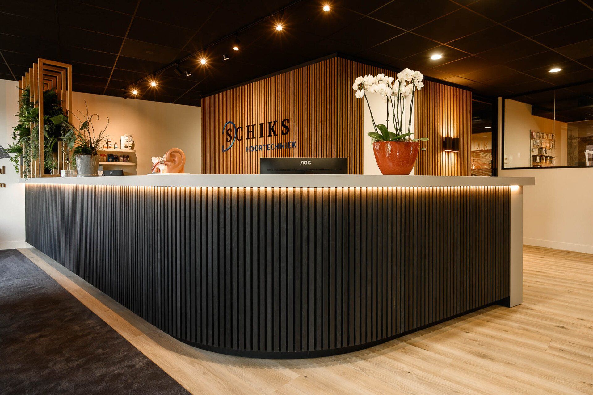 Een receptiebalie met een computer in een kamer met houten wanden.