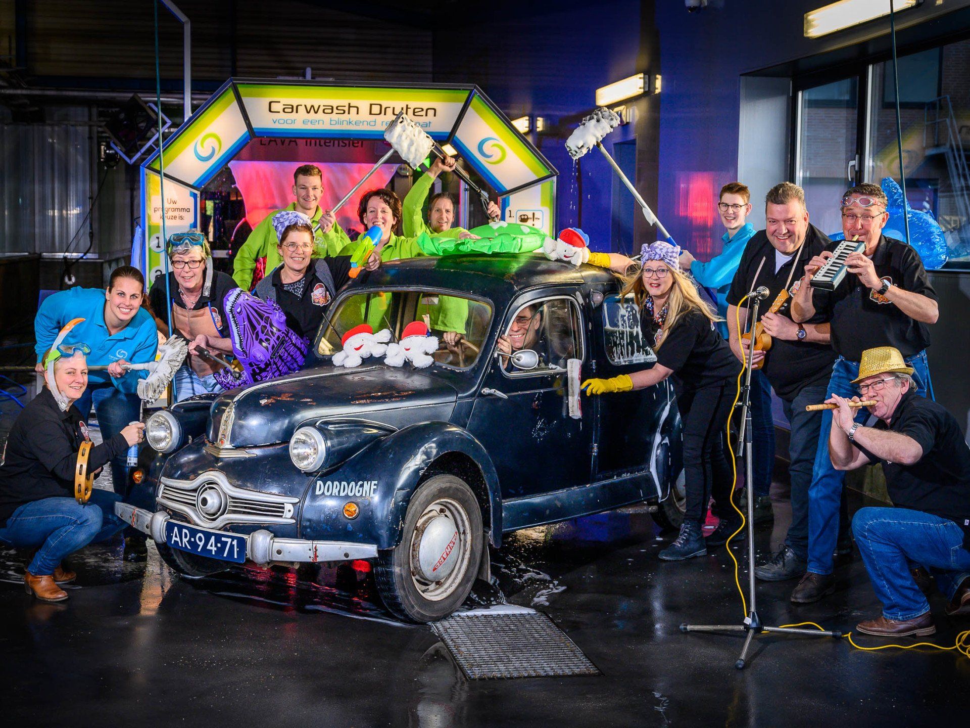Een groep mensen poseert voor een foto voor een auto.