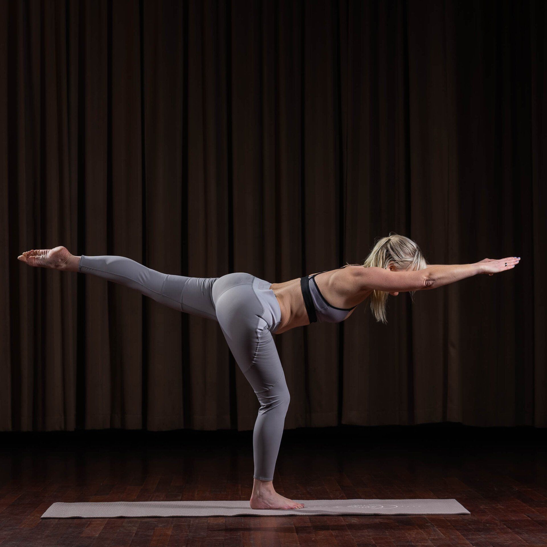 Een vrouw doet een yogahouding op een yogamat.