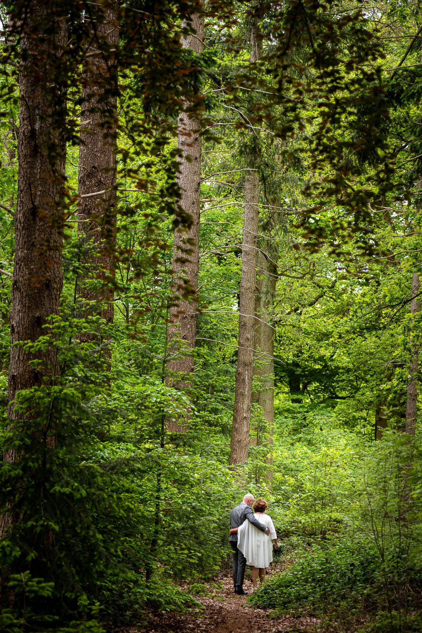 Een man en een vrouw lopen door een bos.