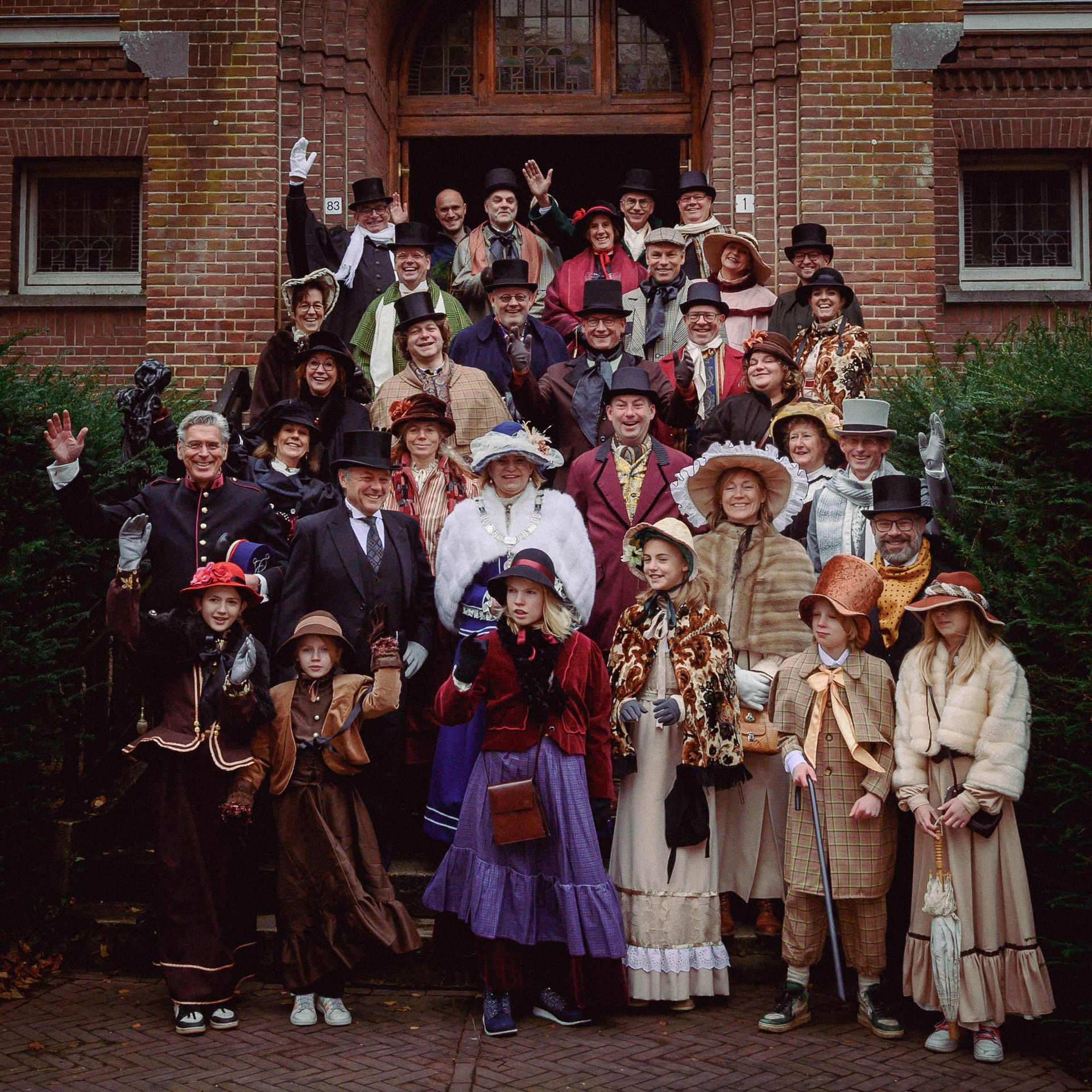 Een grote groep mensen poseert voor een foto voor een gebouw