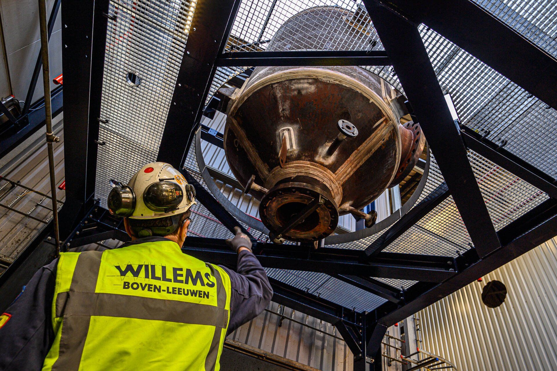 Een man die een geel vest draagt met het woord willems erop werkt aan een machine.