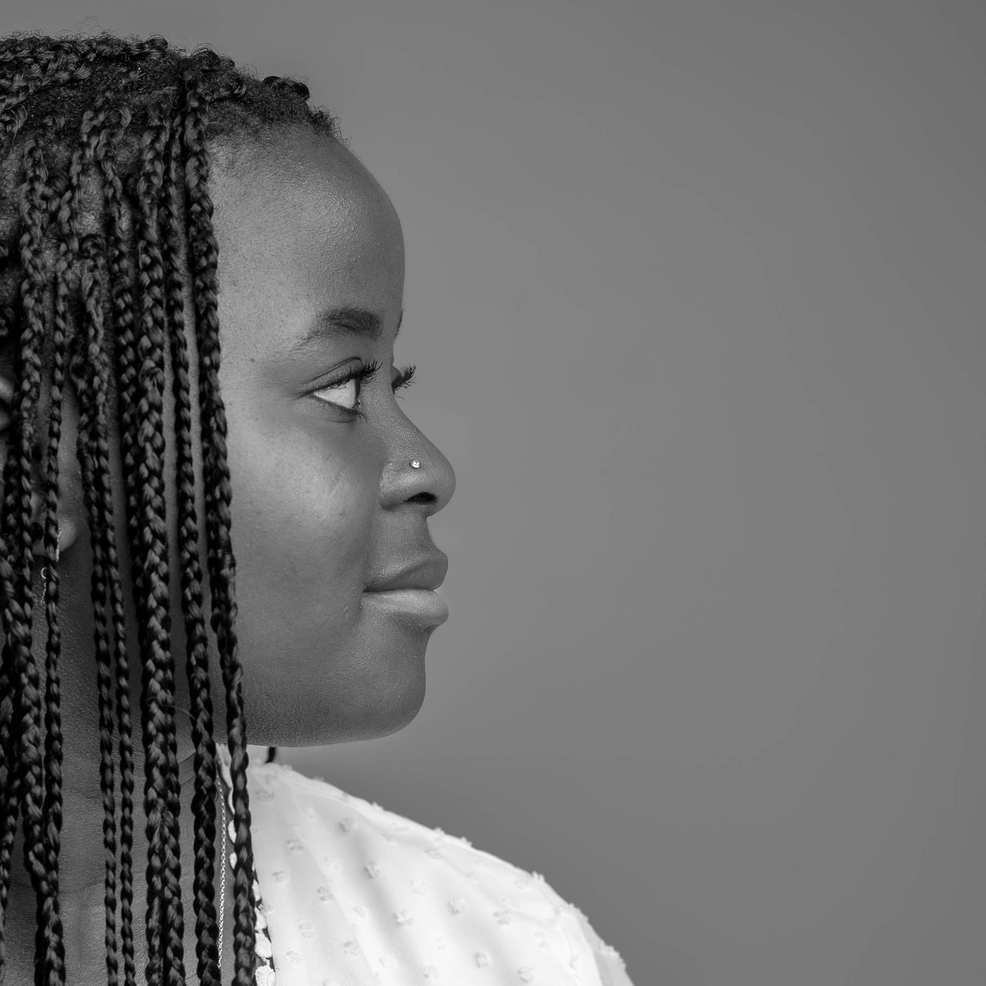 Een zwart-witfoto van een vrouw met vlechten en een neusring.
