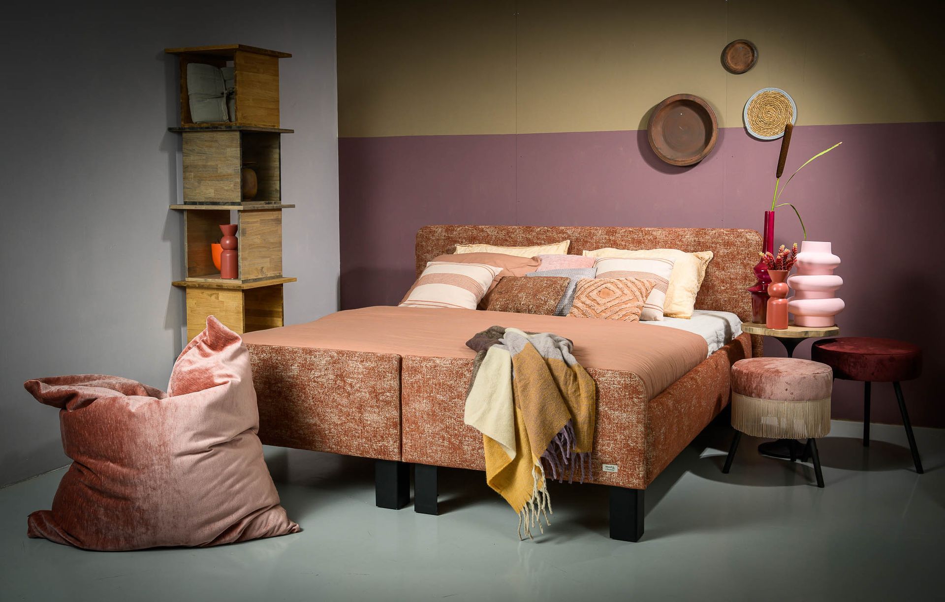 Een slaapkamer met een bed, een voetenbank en een zitzak.