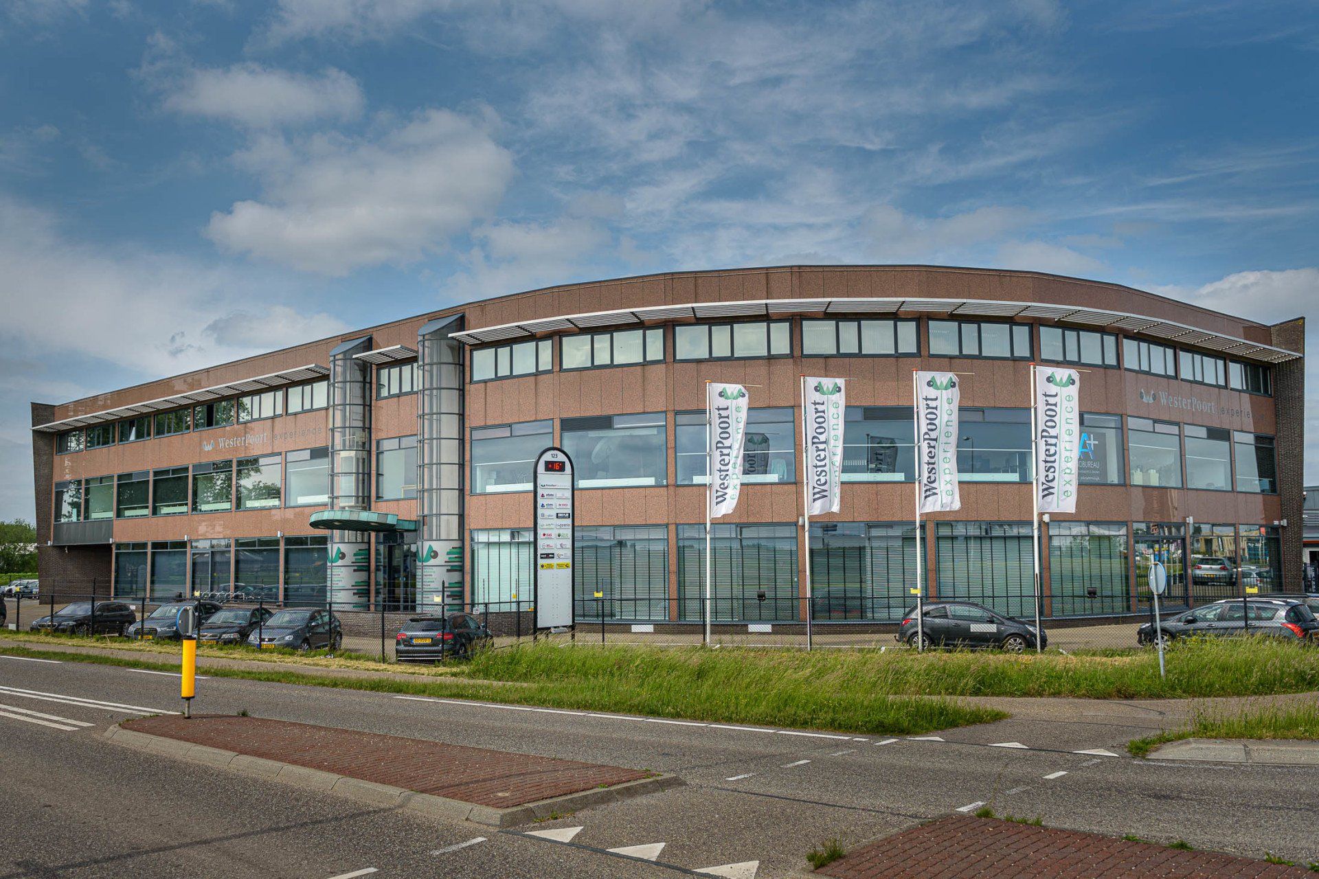 Een groot gebouw met veel ramen en auto's ervoor geparkeerd.