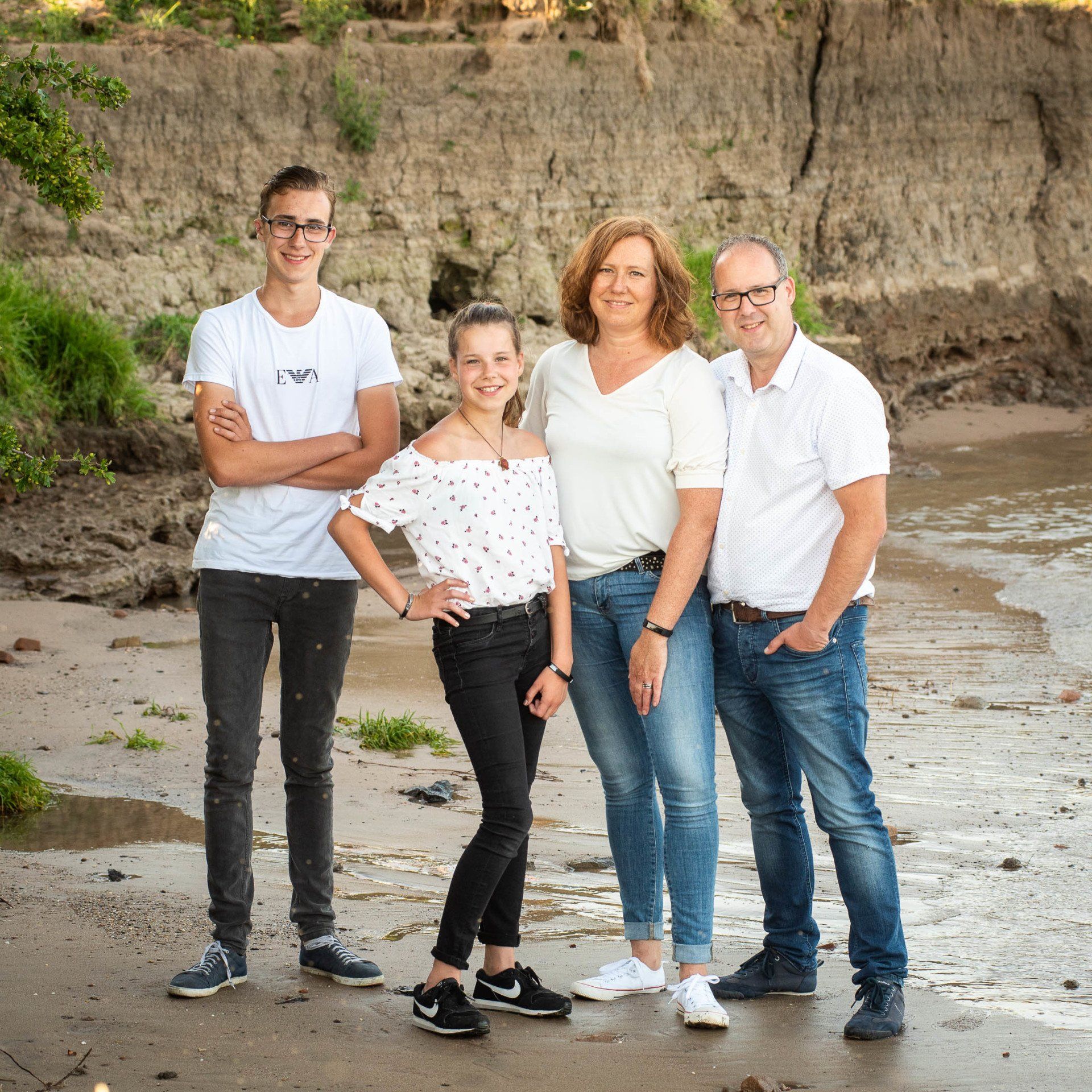 Een gezin poseert voor een foto op het strand.