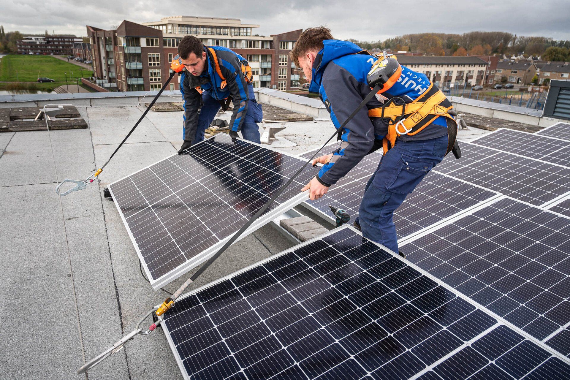 Twee mannen werken op een dak met zonnepanelen.