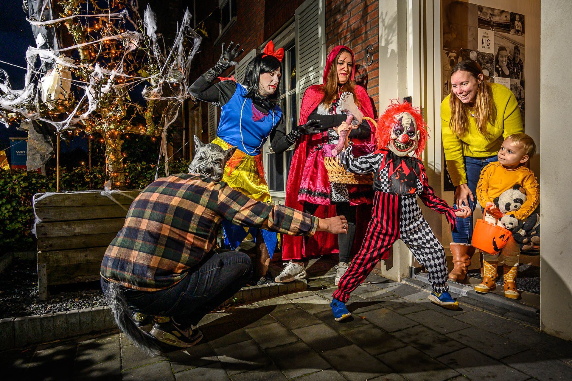 Een groep mensen in Halloween-kostuums staat voor een huis.