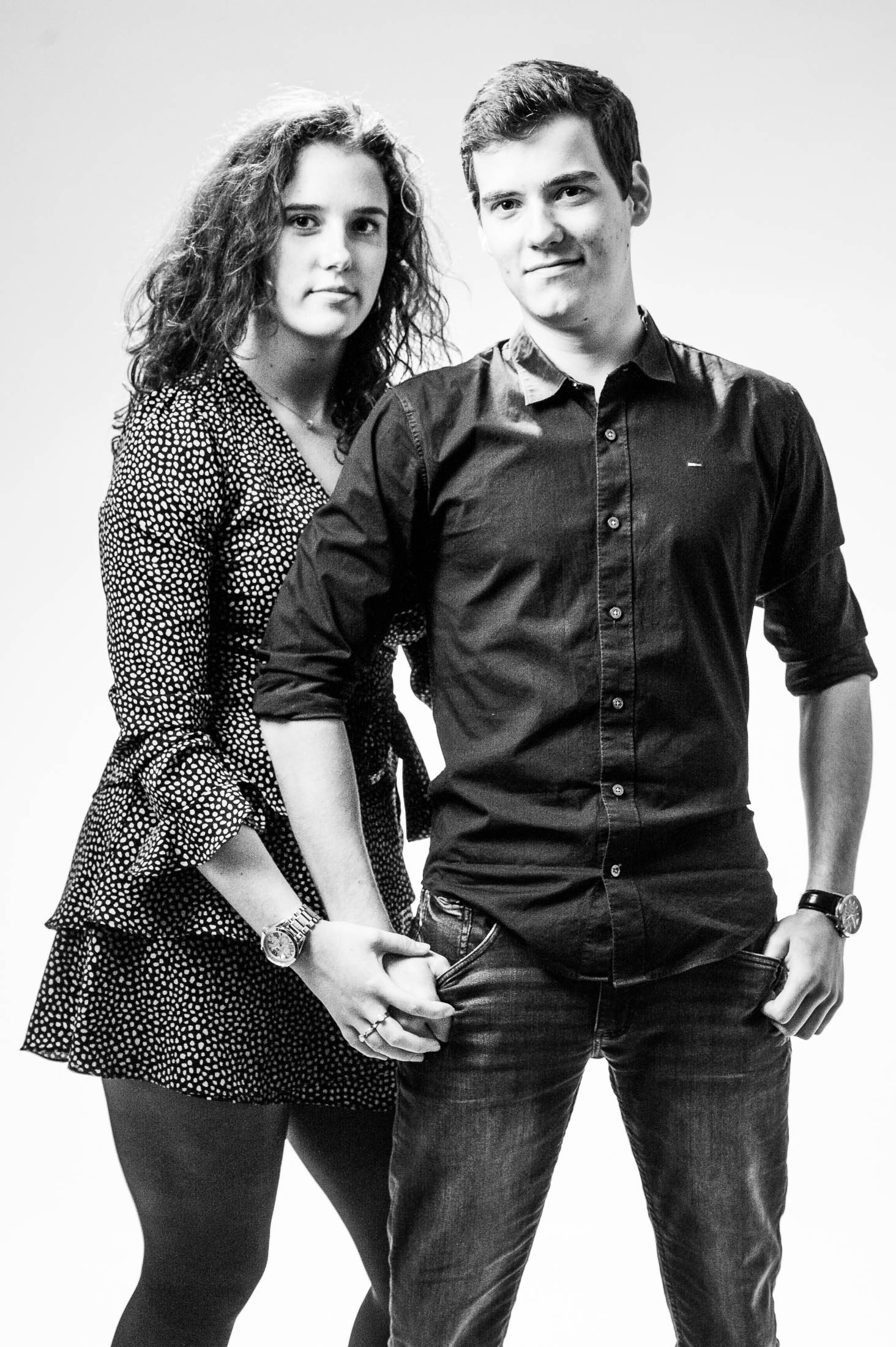 Een man en een vrouw houden elkaars handen vast op een zwart-witfoto.