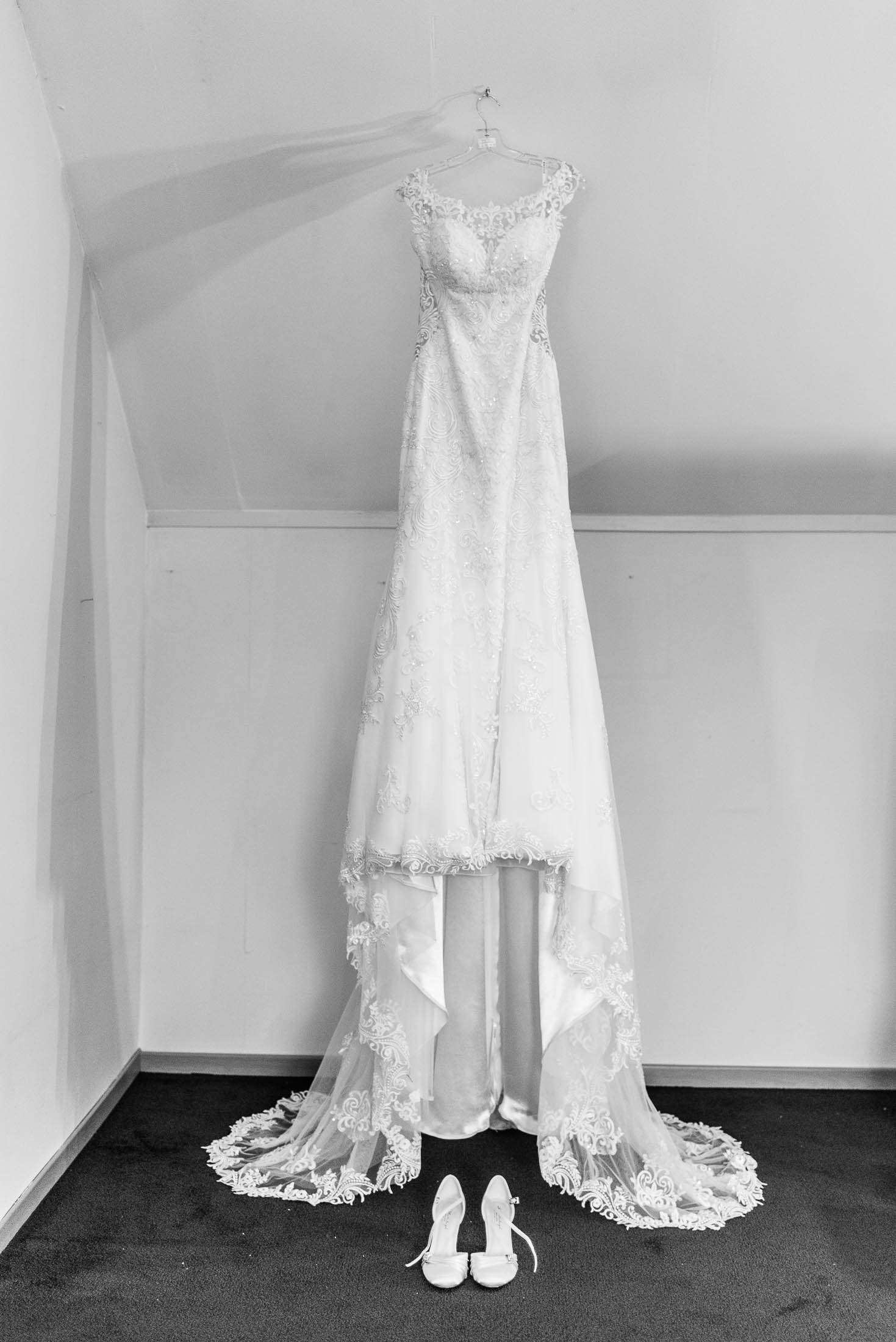 Een zwart-witfoto van een trouwjurk en schoenen.