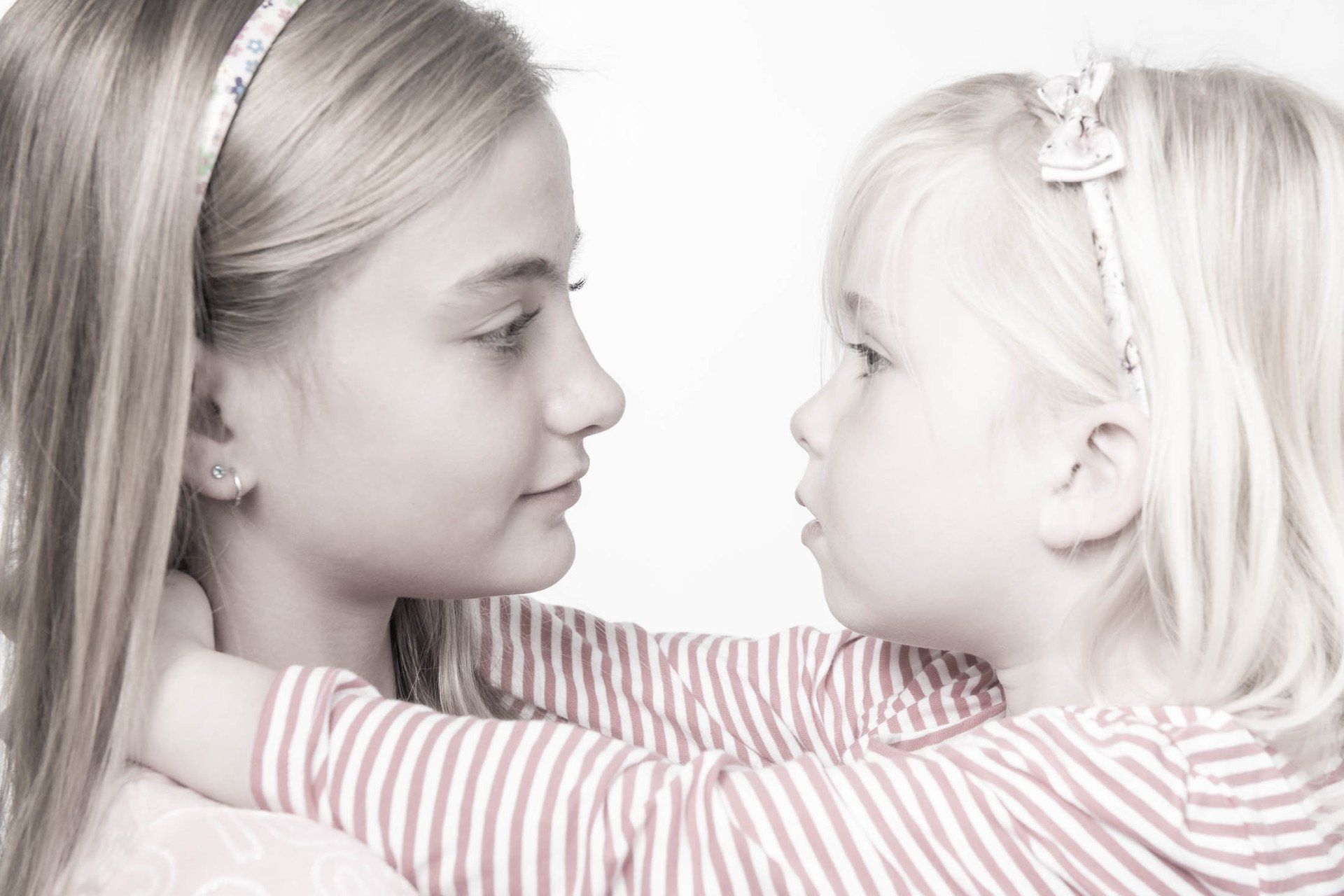 Twee kleine meisjes omhelzen elkaar en kijken naar elkaar.