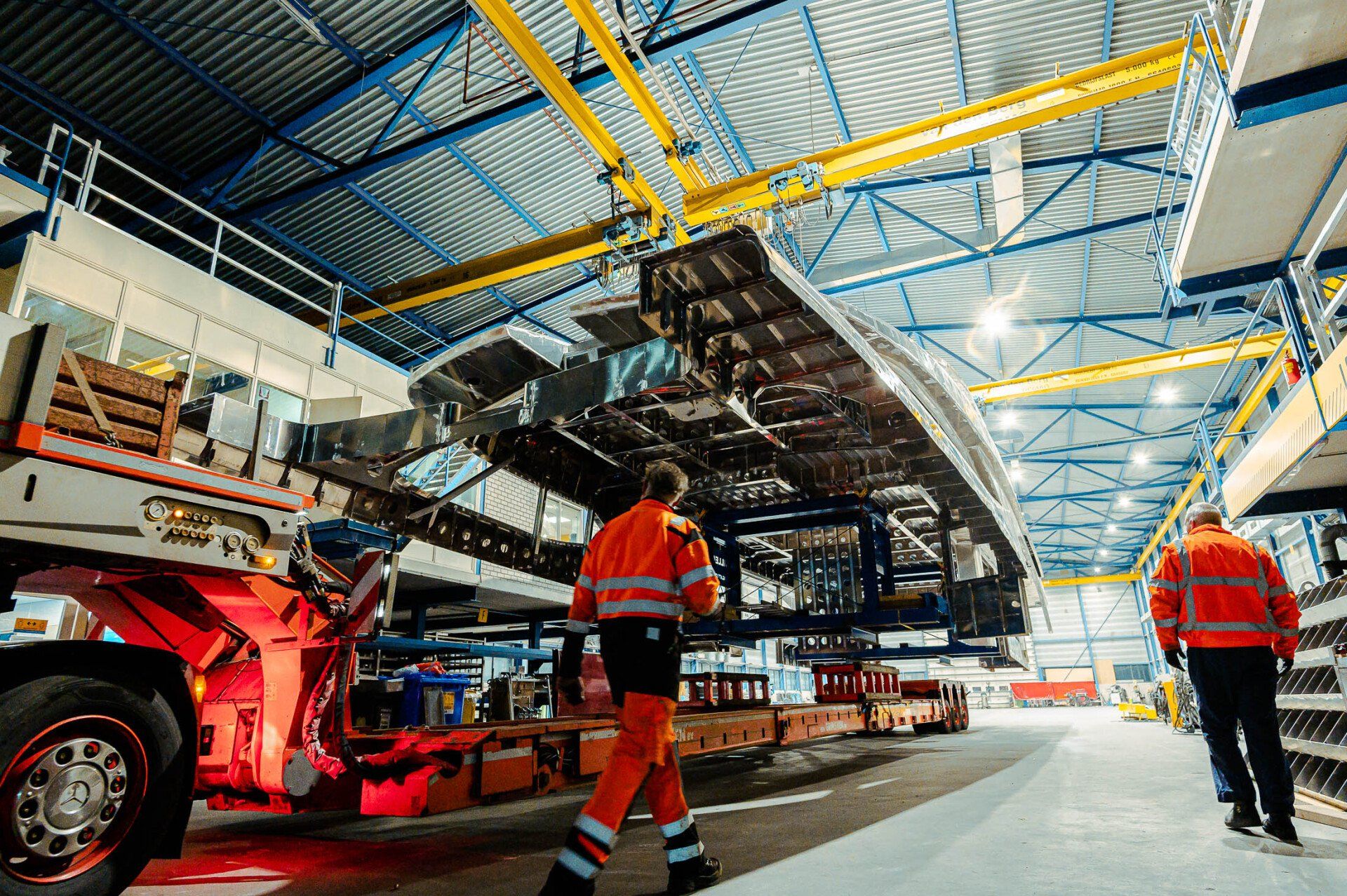 Een man draagt een groot stuk metaal in een fabriek.