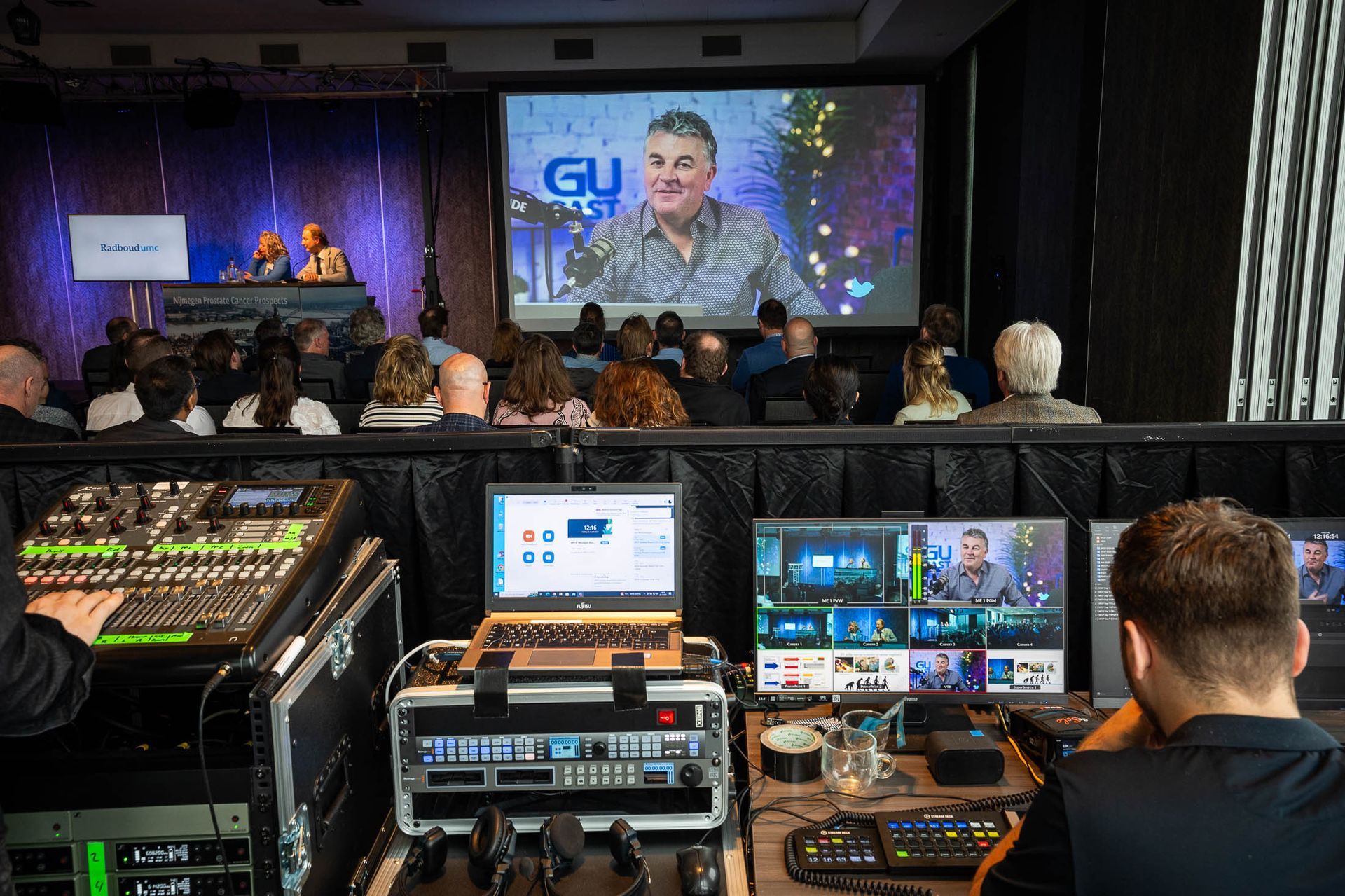 Een man zit voor een groot scherm en bekijkt een presentatie.