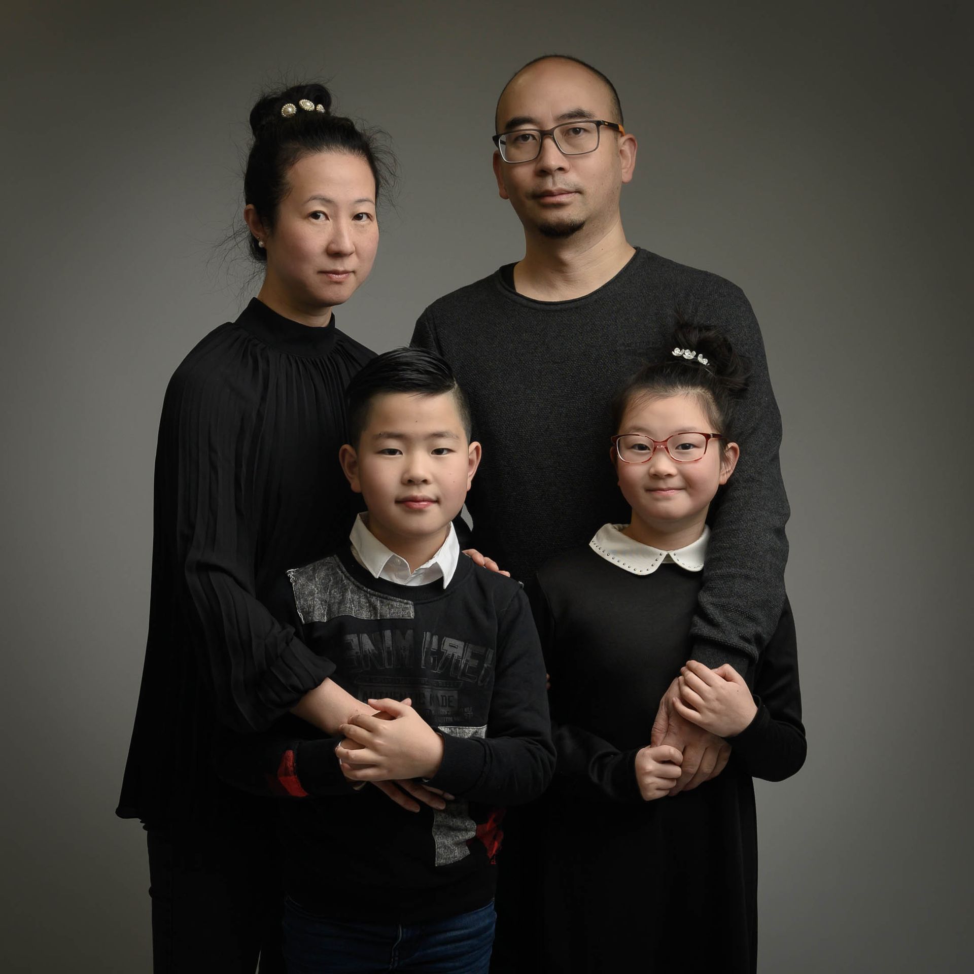 Een gezin poseert voor een foto met een grijze achtergrond