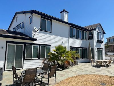 White house with black trim, windows, and a satellite dish, outdoor patio with furniture.