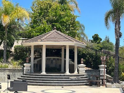 Gazebo with tiered steps, columns, and tiled roof, on a sunny day.