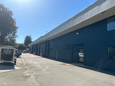 Exterior of blue building with multiple garage doors, sunny day.