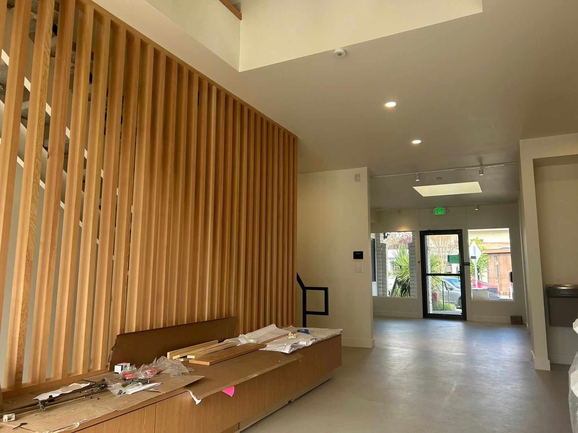 Interior view of a modern space with wooden slat wall, unfinished cardboard, and a hallway leading to an exit.