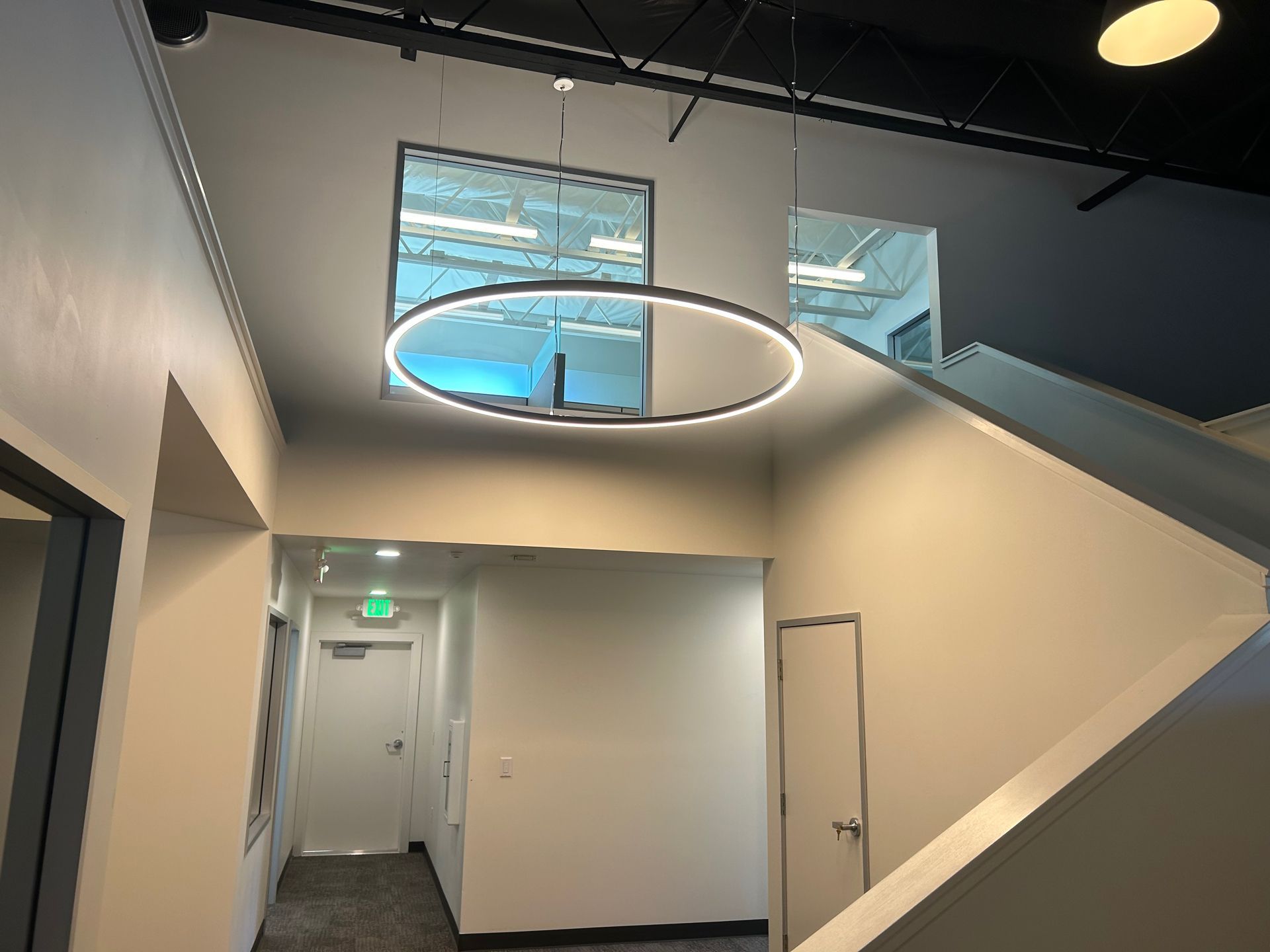 Interior hallway with white walls, recessed lighting, a stairway, and a round pendant light.