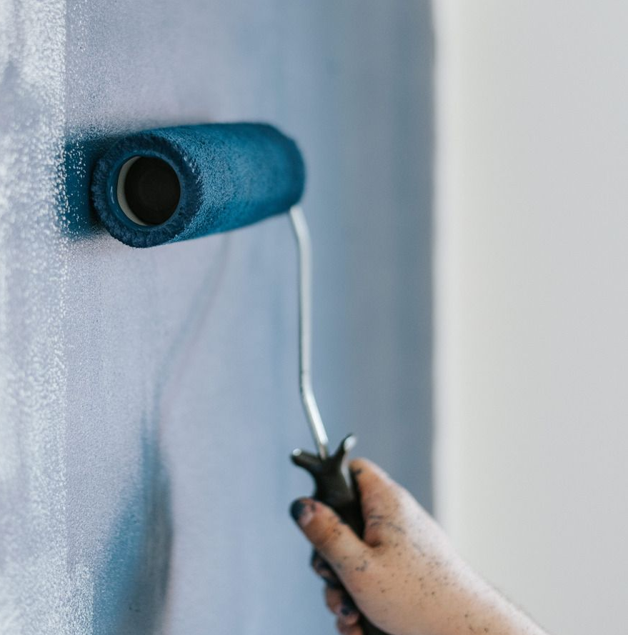A delivery man in a red shirt is writing on a clipboard