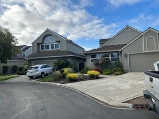 Houses on a street, with cars parked in driveways and a cloudy sky overhead.