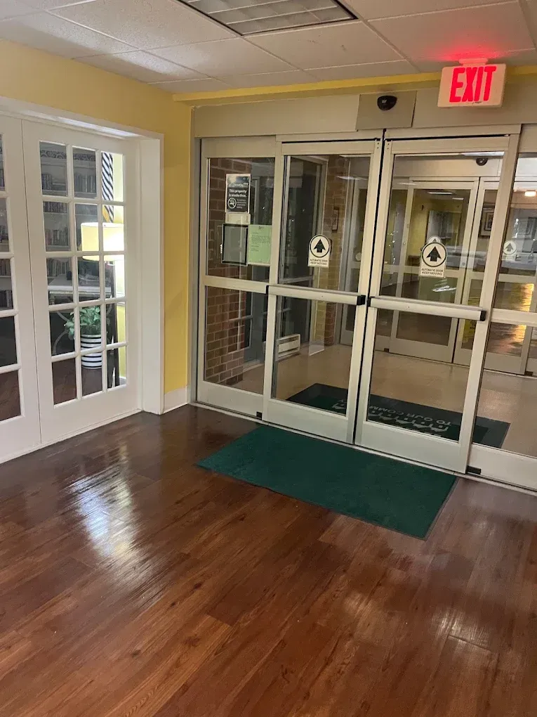 Entrance with sliding glass doors, wooden floor, and an exit sign.