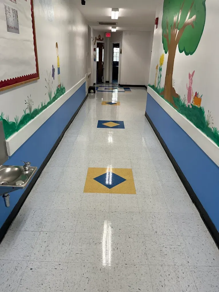 Hallway with blue and white walls, colorful mural, terrazzo floor with yellow and blue squares.