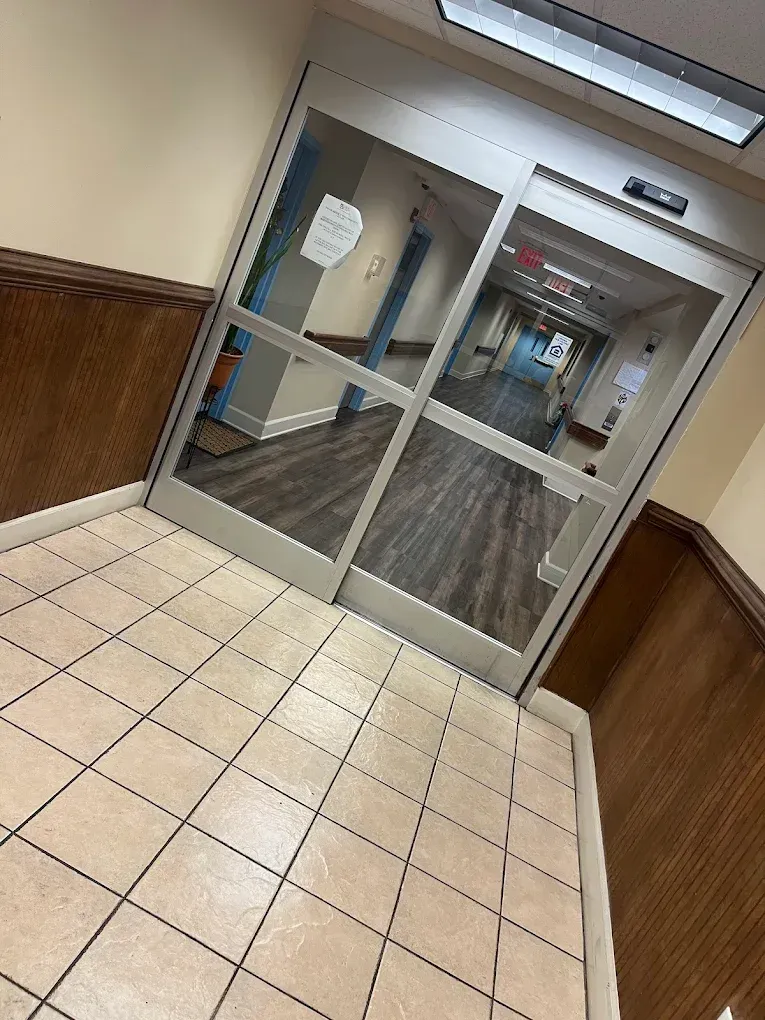 Sliding glass doors open to a hallway with wooden floors and walls.