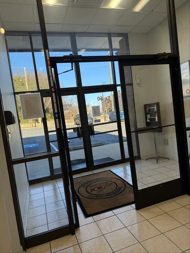 Entrance to a building with glass doors, a welcome mat, and tiled floor, with a view of the street outside.